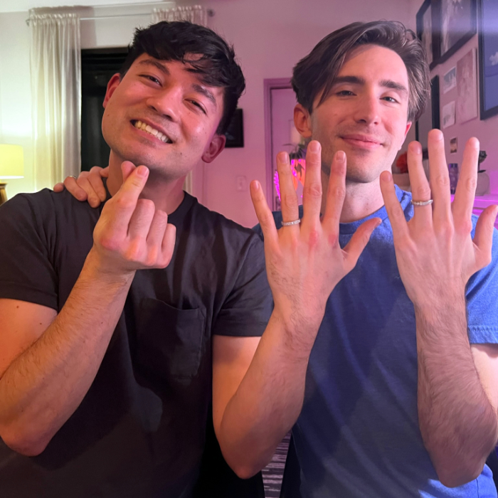 Justin and Tyler holding up their hands to show off their wedding rings
